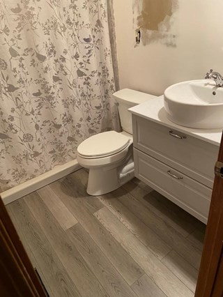Bathroom renovation with new flooring and white fixtures.