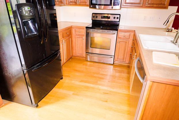 Kitchen with wood cabinets, appliances, and light wood flooring.