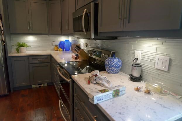Modern kitchen with dark cabinets and white countertops.
