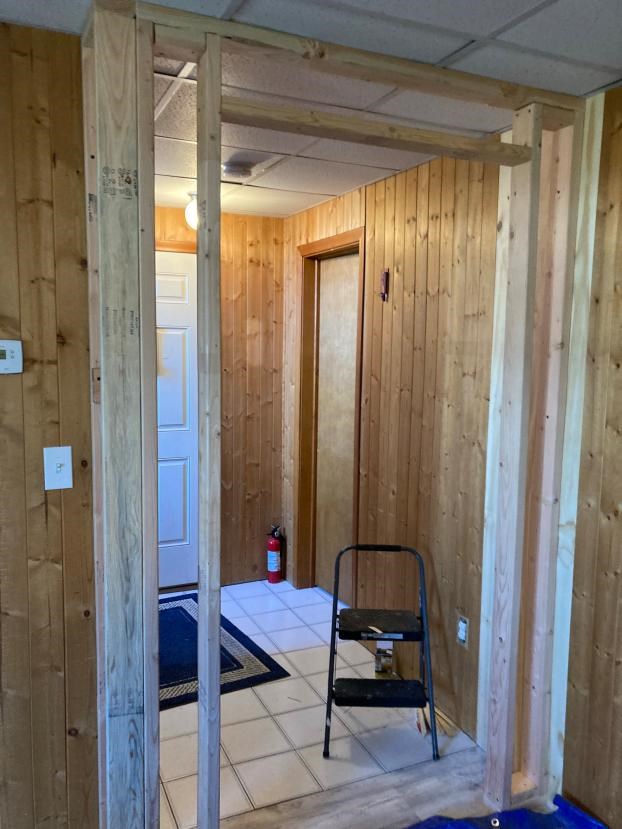 Wooden doorway frame in progress in a paneled room.