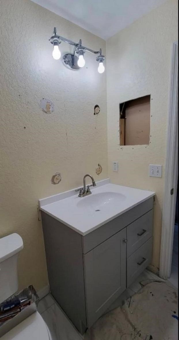 Bathroom remodel with vanity, missing mirror, and exposed wall.