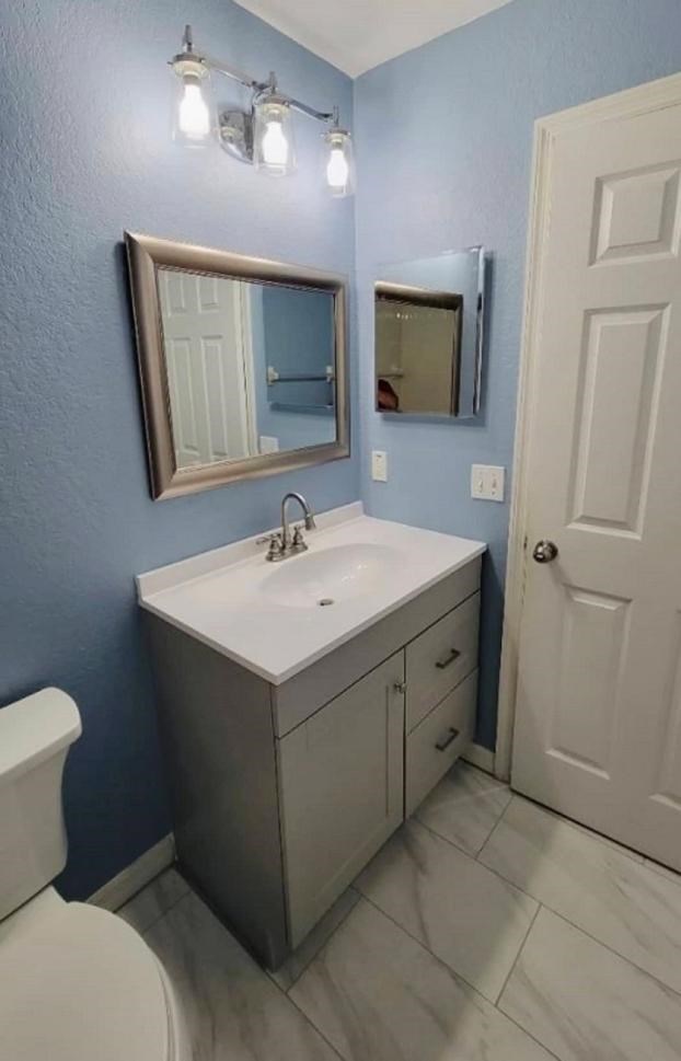 Bathroom with blue walls, vanity, and mirror renovations.